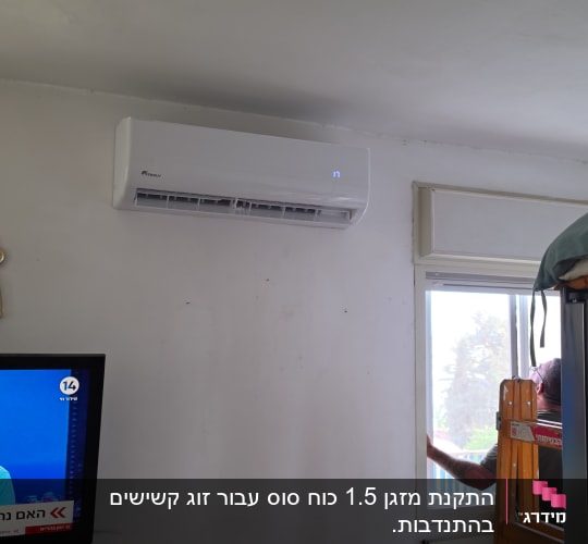 התקנת מזגן עילי בחדר מגורים עם טכנאי העובד בחלון